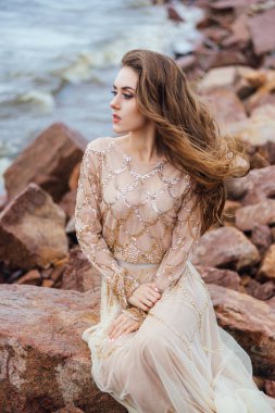 genç güzel kadın gelinlikle deniz kıyısında günbatımı poz 