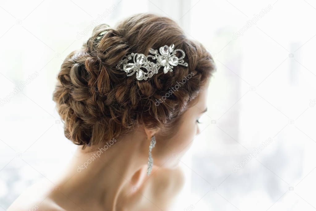 photo of young attractive bride with wedding hairstyle in light room