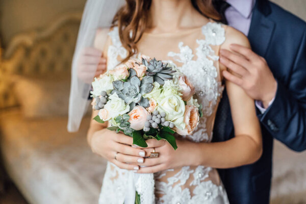 close-up photo of young stylish couple holding flowers bouquet at wedding day