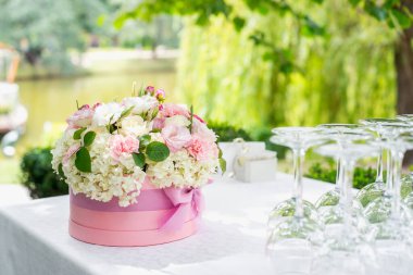 Çiçek aranjmanı açık havada, masanın üstünde bir şapka kutusunda. Restoranın yaz terası.