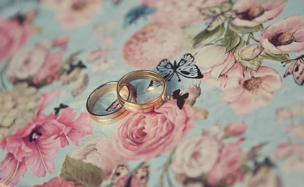 青い蝶背景のホワイト ・ ゴールドの 2 つの結婚指輪 — ストック写真