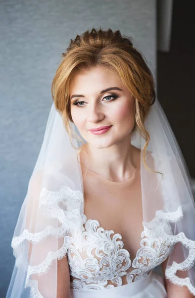 Noiva feliz com belo sorriso em um belo vestido de noiva branco na parede cinza fundo. Lace lindo decotado — Fotografia de Stock