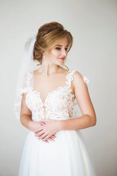 Noiva feliz com belo sorriso em um belo vestido de noiva branco no fundo parede branca. Lace lindo decotado — Fotografia de Stock