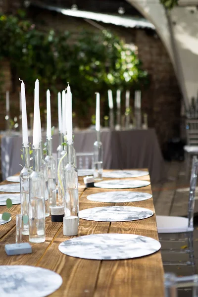 Candele bianche in bottiglie di vino stand su tavolo bianco — Foto Stock