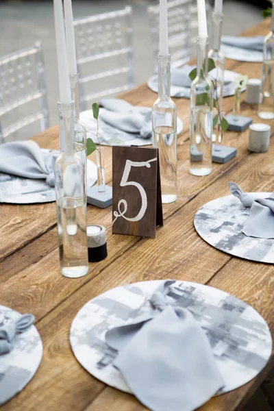 Mesa con comida y flores en la boda. Número 5 escrito en la tarjeta blanca se para ante el ramo en el centro de la mesa de la cena — Foto de Stock