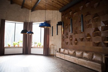 Çatı katı tarzında iç. Yüksek tavanlı, geniş pencereler, çatı armatürleri avizeler, eski deri vintage eski püskü kanepe