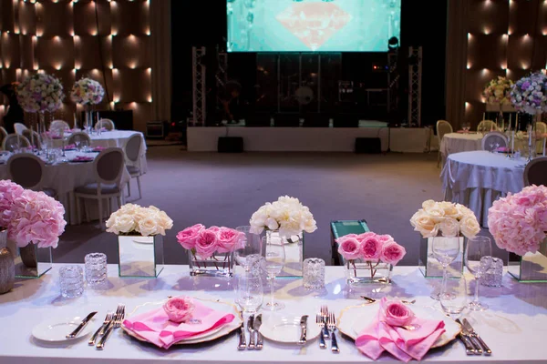 Mooie tafel setting met een wit tafellaken en roze servetten. Rood bestek, mooie eetkamer gebruiksvoorwerpen. Bruiloft Decoratie textiel — Stockfoto