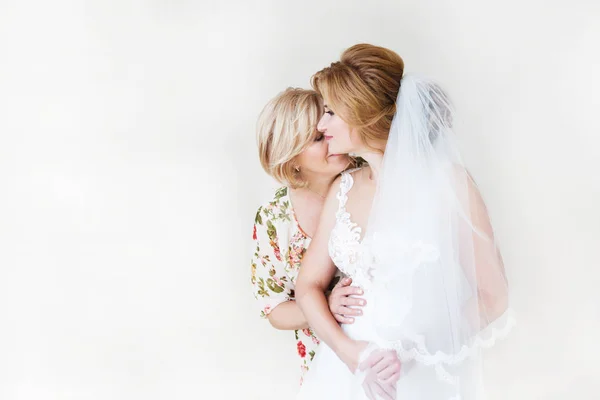 Mamá felicita a las novias con un matrimonio y abrazos. Mujer bienvenida. Mamá abraza a su hija. En el fondo una pared de luz — Foto de Stock