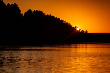 Segovia rezervuarında gün batımı, Sierra de Guadarrama ulusal parkında. Sıcak tonlu fotoğraf, yürüyen insanların siluetleri.