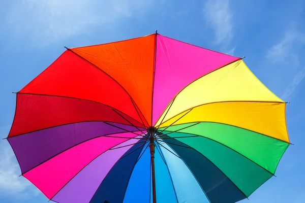 Aperto ombrello arcobaleno colorato su sfondo cielo blu — Foto Stock