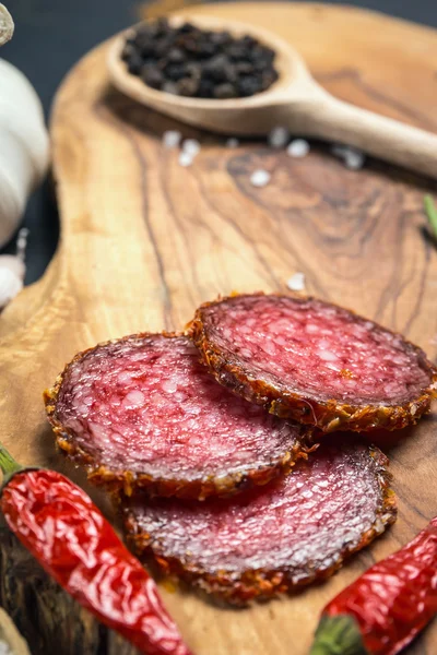 Salame seco crostado em pimenta vermelha moída em fundo escuro — Fotografia de Stock