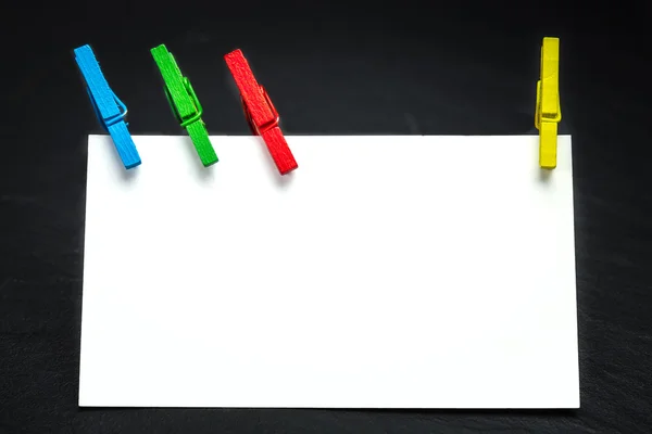 Close up of a note paper and clothes pegs on a black background — Stock Photo, Image