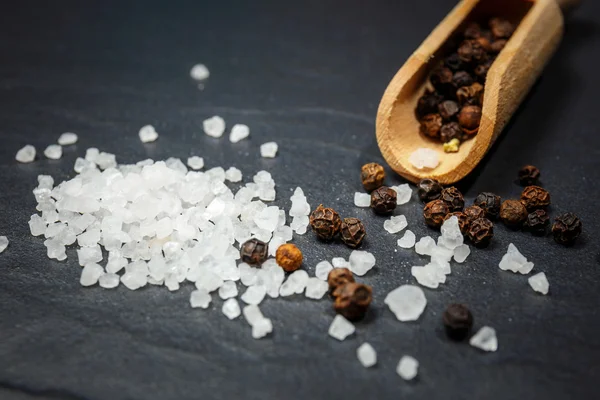 Black pepper and salt on rustic stone background. Overhead view food photography. — Stock Photo, Image
