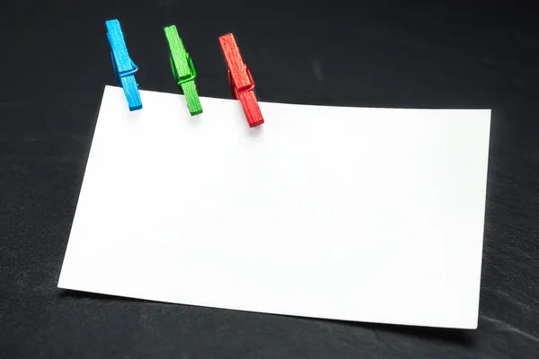 Close up of a note paper and clothes pegs on a black background — Stock Photo, Image