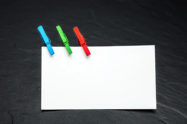 Close up of a note paper and clothes pegs on a black background — Stock Photo, Image