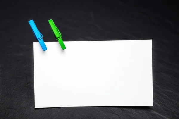 Close up of a note paper and clothes pegs on a black background — Stock Photo, Image