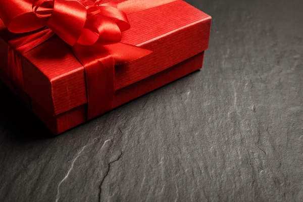 Rode geschenkdoos met lint op donkere stenen achtergrond met kopie ruimte — Stockfoto