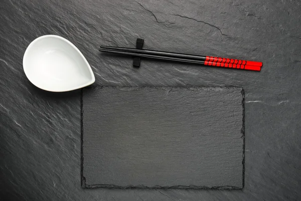 İki çubuk ve boşaltmak, üstten görünüm siyah taş zemin üzerine beyaz kase