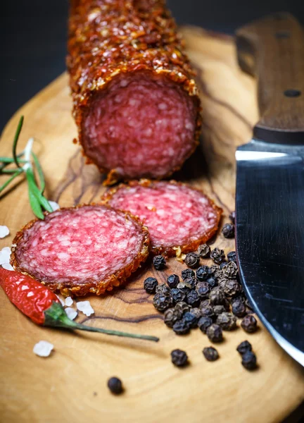 Salame seco crostado em pimenta vermelha moída em fundo escuro — Fotografia de Stock