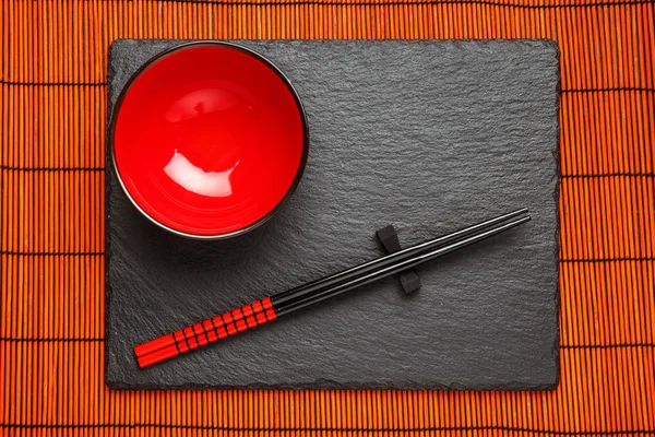 Dua sumpit dan piring merah di latar belakang batu hitam dengan ruang penyalinan — Stok Foto