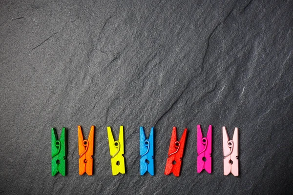 Colorful clothes pegs on black board, top view — Stock Photo, Image