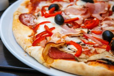 Pizza beyaz plaka üzerinde kırmızı taze biber ve Siyah Zeytin ile