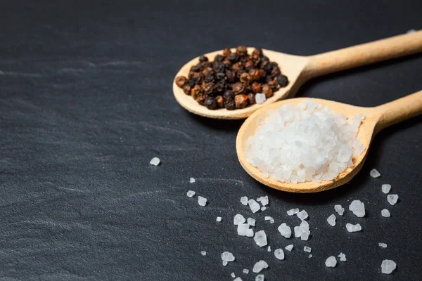 Black pepper and salt on rustic stone background. Overhead view food photography — Stock Photo, Image