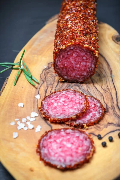 Salame seco crostado em pimenta vermelha moída em fundo escuro — Fotografia de Stock