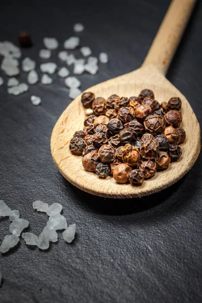 Black pepper and salt on rustic stone background. Overhead view food photography — Stock Photo, Image