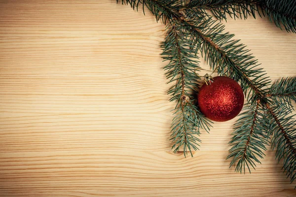 Christmas wooden background with fir tree and red bauble — Stock Photo, Image