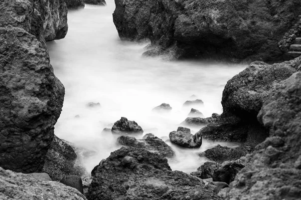 Movimiento borroso agua que rodea las rocas, blanco y negro — Foto de Stock