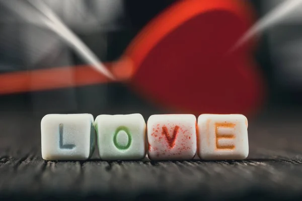 Palabra Amor escrito en bloques de cerámica con el corazón fuera de foco en el fondo —  Fotos de Stock
