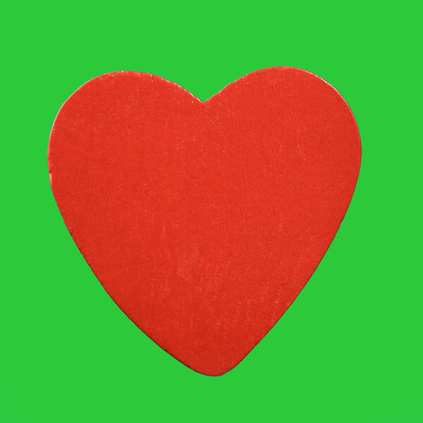 Red wooden heart isolated on green background