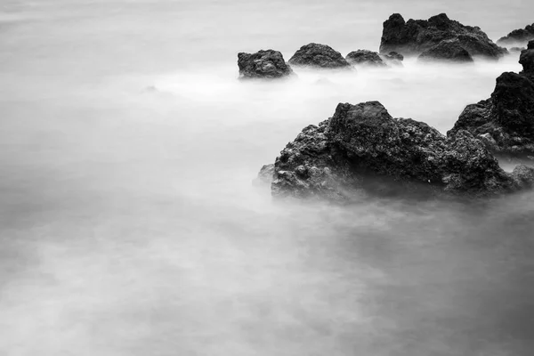 Moto acqua sfocata che circonda rocce, bianco e nero — Foto Stock