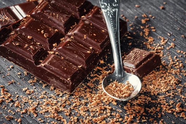 Close up of dark chocolate and spoon on dark wooden background — Stock Photo, Image