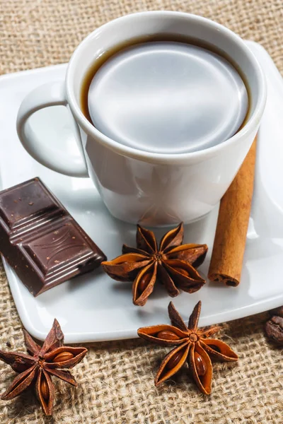 Xícara de café com anis, chocolate e canela em uma mesa de madeira — Fotografia de Stock