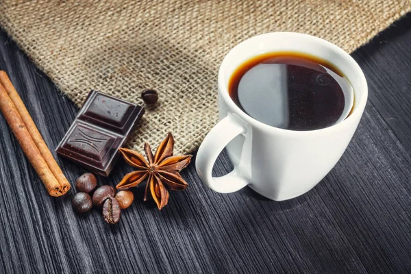 Xícara de café com anis, chocolate e canela em uma mesa de madeira — Fotografia de Stock