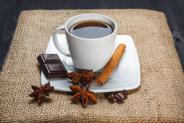 Tasse Kaffee mit Anis, Schokolade und Zimt auf einem Holztisch — Stockfoto