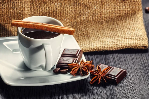 Tasse Kaffee mit Anis, Schokolade und Zimt auf einem Holztisch — Stockfoto