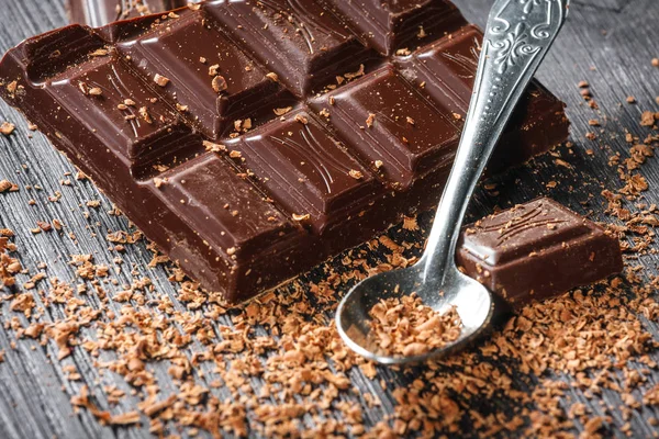 Close up of dark chocolate and spoon on dark wooden background — Stock Photo, Image