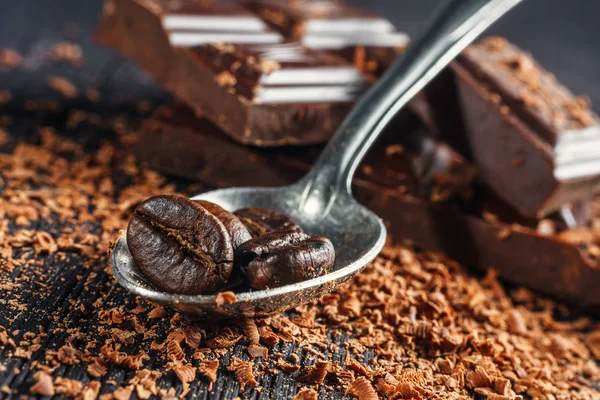 Coffee beans on spoon and chocolate, close up — Stock Photo, Image