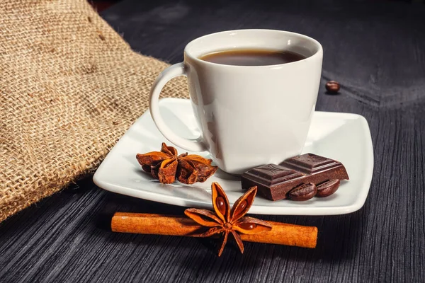 Xícara de café com anis, chocolate e canela em uma mesa de madeira — Fotografia de Stock