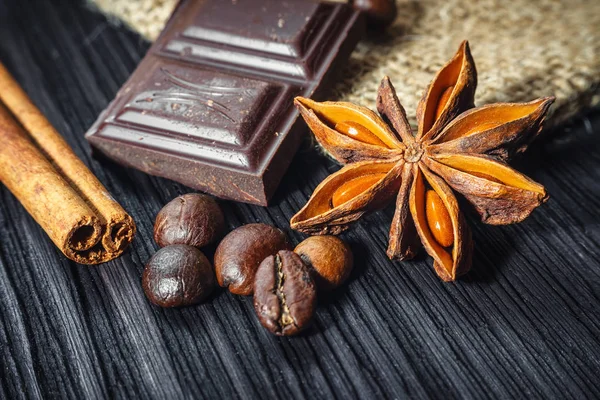 Chocolate bar and spices on wooden table, close up — Stock Photo, Image