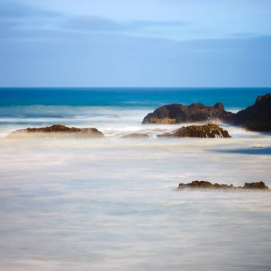 Los Hervideros, dalgalı okyanus ve mavi gökyüzü, uzun süreli pozlama ile volkanik kıyı şeridi