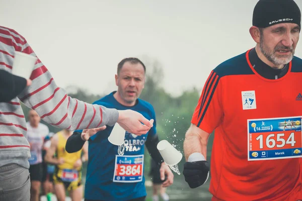 Krakau, Polen - 30. April 2017: Unbekannter Marathonläufer sammelt Wasser an Servicestelle während des Krakauer Marathons ein. Der Marathon ist ein jährliches Ereignis. — Stockfoto