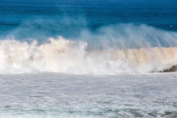 Blue wave crashes down at the beach in El Cotillo village in Fuerteventura island, Spain — стоковое фото