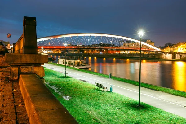 Бернатский пешеходный мост через Вислу ночью в Кракове, Польша — стоковое фото