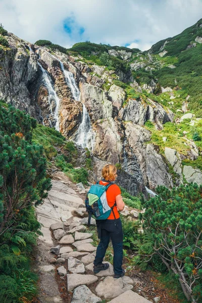 Vrouw staat op het pad en kijkt naar de toppen van bergen — Stockfoto