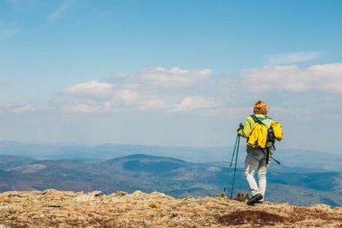 kadın yol üzerinde duruyor ve dağlar başında görünüyor