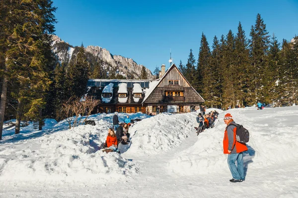 Tatry, Polska, 14 lutego 2015: grupa turystów siedzieć przed schronisko górskie i cieszyć się słońcem, doliny Kościeliskiej, Polska — Zdjęcie stockowe